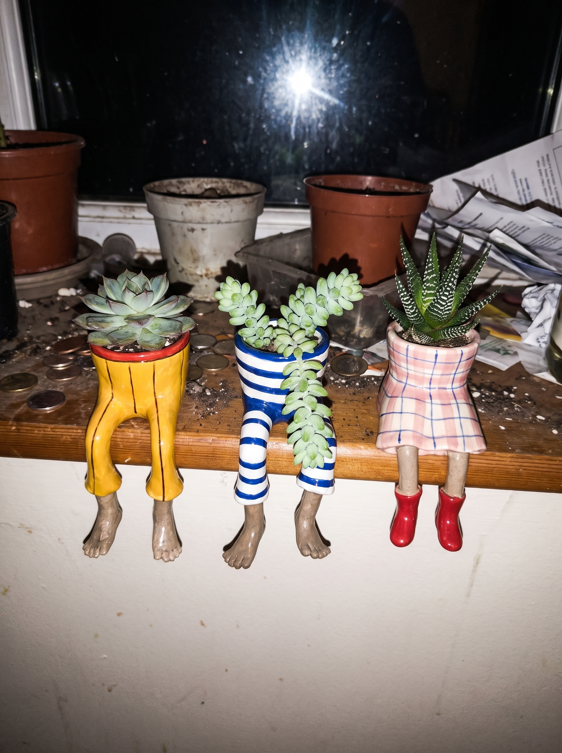Three dangling-legs plant pots on a windowsill